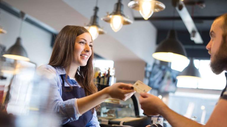 naiset vastaanottavat korttimaksuja miehille kahvilassa